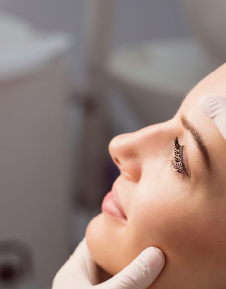 Hands of doctor examining womans face for cosmetic treatment at clinic